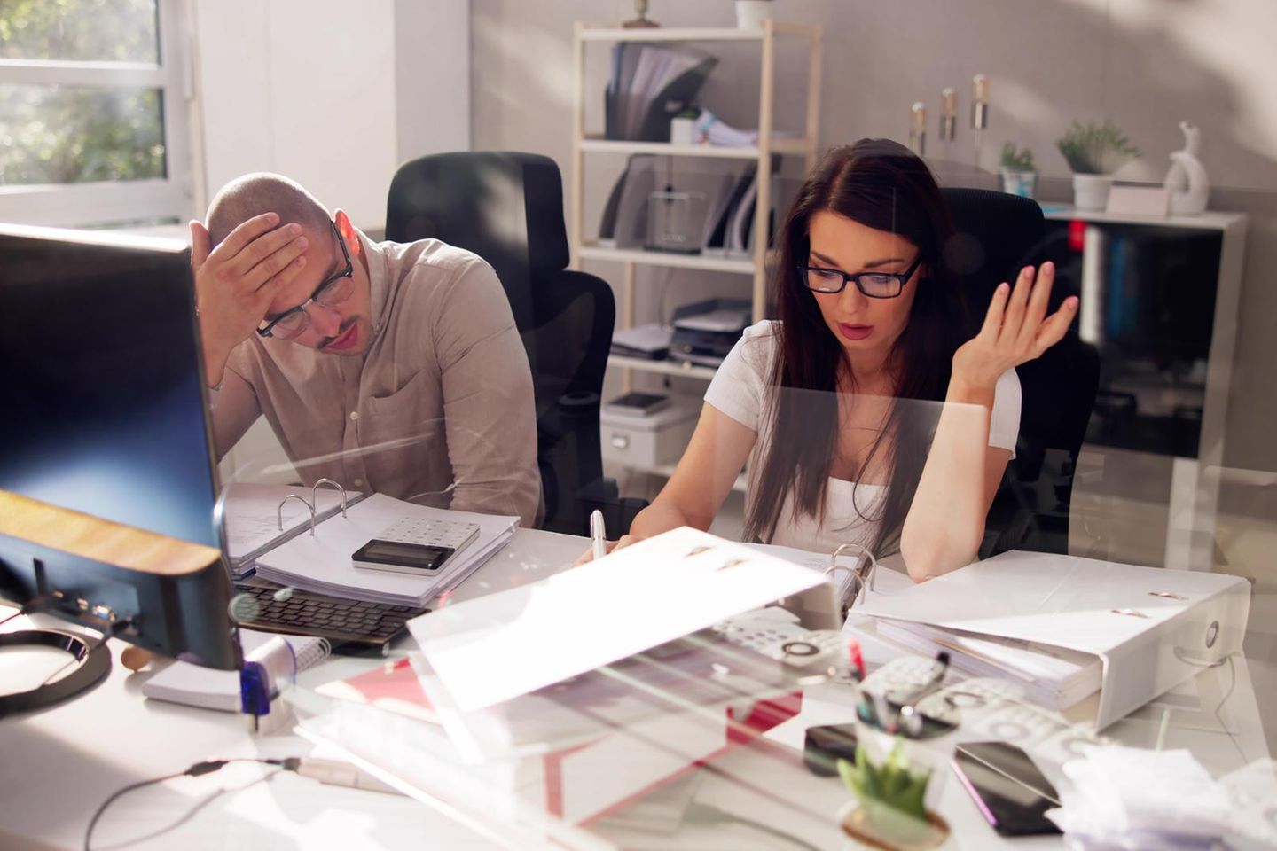 Ein Mann und eine Frau sitzen an ihrem Schreibtisch im Büro
