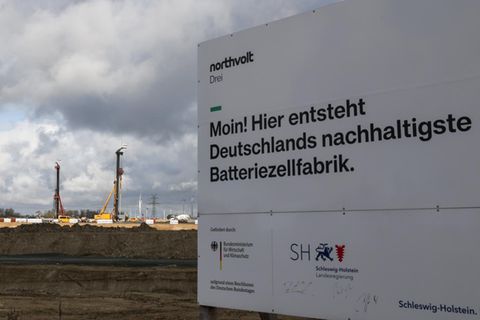 Ein Bauschild mit dem Text „Moin! Hier entsteht Deutschlands nachhaltigste Batteriezellenfabrik“ steht an der Baustelle in Heide