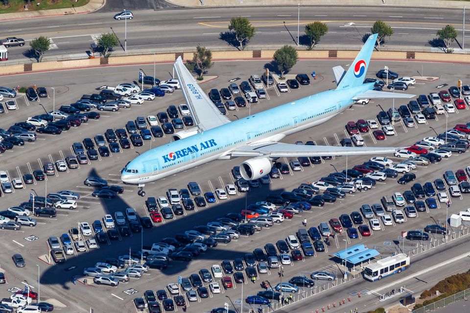 Ein Flugzeug der Korean Air fliegt über einen Parkplatz