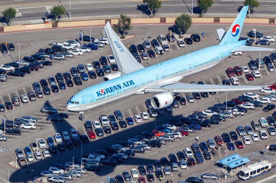 Ein Flugzeug der Korean Air fliegt über einen Parkplatz
