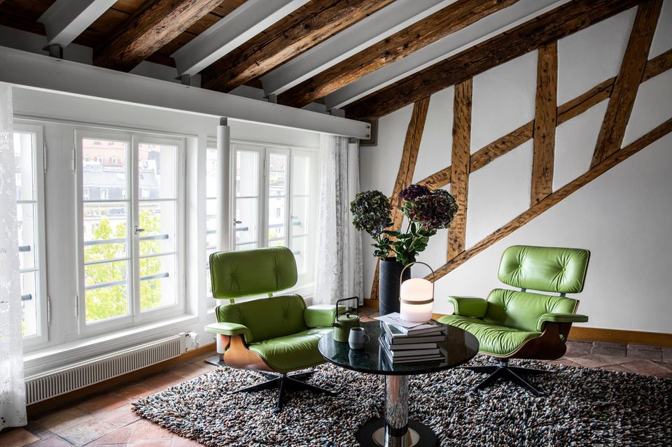 Mit grünem Leder bezogene Designersessel und ein großes Bett unter Holzbalken – der Courtyard Queen Room