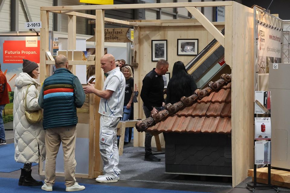 Besucher informieren sich an einem Dachdeckerstand auf der Messe "Haus.Bau.Ambiente“