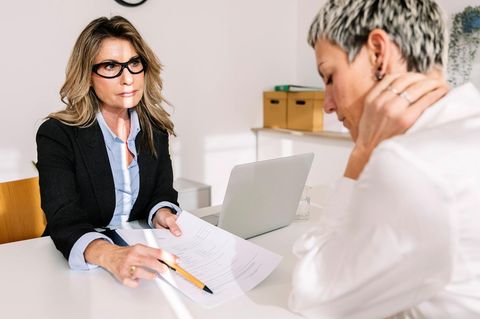 Zwei Frauen im Büro, die eine hält den Arbeitsvertrag in der Hand, die andere überlegt
