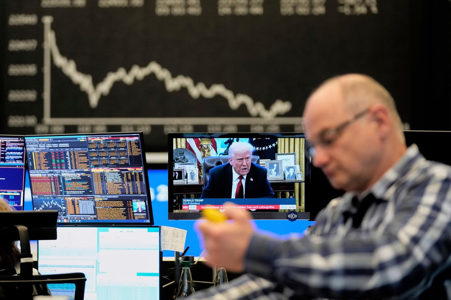 Ein Börsenhändler in der Frankfurter Börse vor einem Fernseher, auf dem Trump zu sehen ist