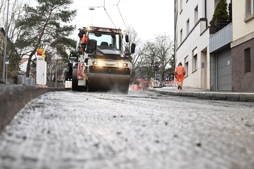 Eine Walze glättet und verdichtet neu aufgebrachten Straßenbelag an einer Baustelle zur Erneuerung einer Straße.