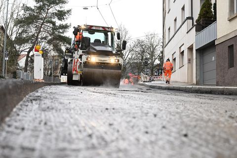 Eine Walze glättet und verdichtet neu aufgebrachten Straßenbelag an einer Baustelle zur Erneuerung einer Straße.