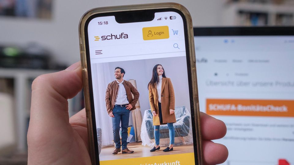 Mobiltelefon in einer Hand mit der Website der Schufa