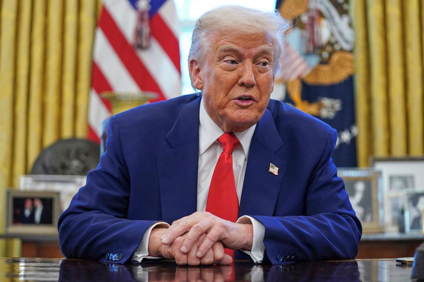 Donald Trump sitzt am Schreibtisch im Oval Office und spricht