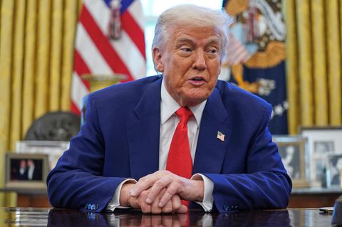 Donald Trump sitzt am Schreibtisch im Oval Office und spricht