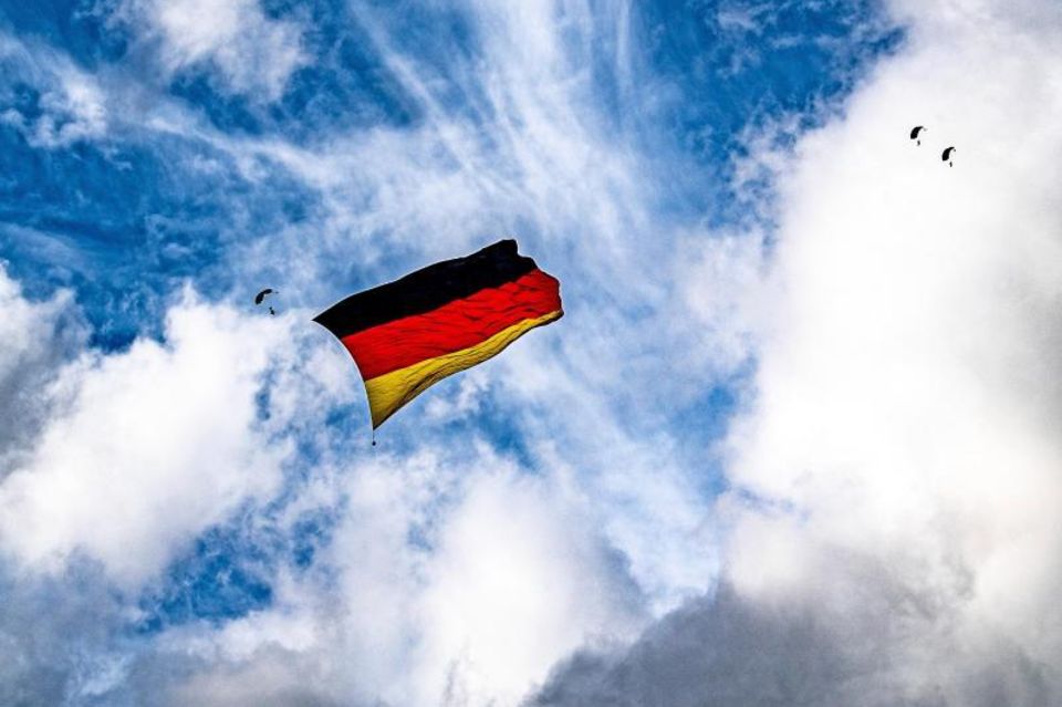 High up: Parachutists unfold a German flag