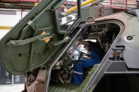 Ein Mitarbeiter von Rheinmetall arbeitet an einem Panzer vom Typ Fuchs