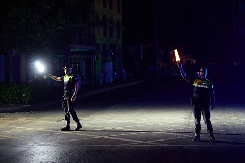 Zwei Polizisten auf der Straße halten während des Blackouts Lampen in der Hand – um sie rum ist alles finster