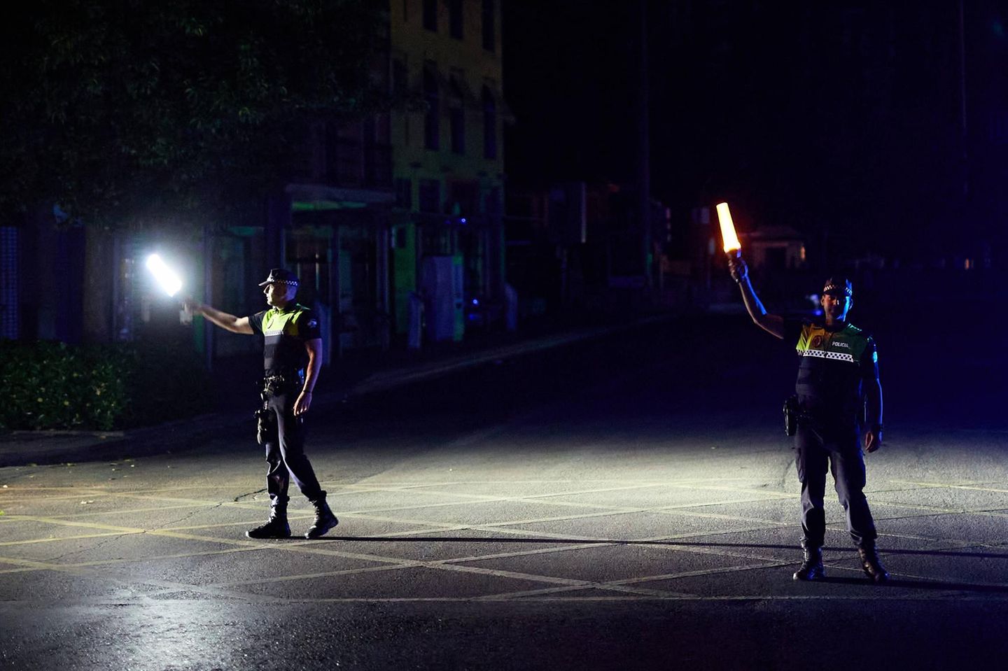 Zwei Polizisten auf der Straße halten während des Blackouts Lampen in der Hand – um sie rum ist alles finster