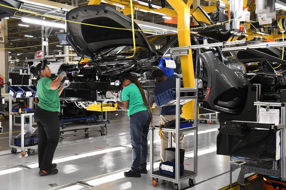 Mercedes-Arbeiterinnen am Fließband bauen Teile in ein neues Elektrofahrzeug ein