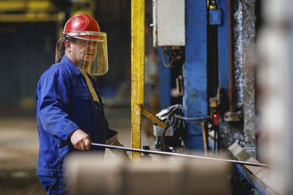 Ein Arbeiter steht an einem Kessel waehrend eines Verzinkungs-Vorgangs