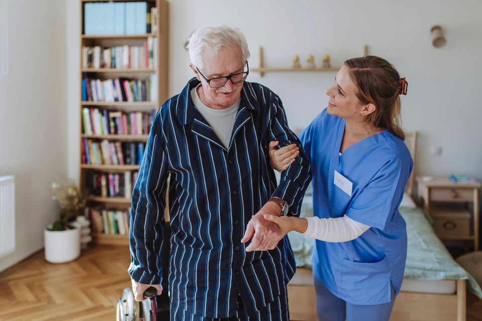 Lächelnde Pflegekraft, die sich um einen älteren Mann kümmert