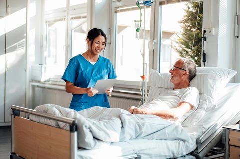 Krankenschwester, die einen Patienten in einem Krankenhauszimmer behandelt