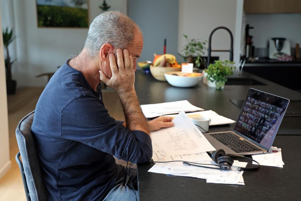 A man participates in a meeting via laptop