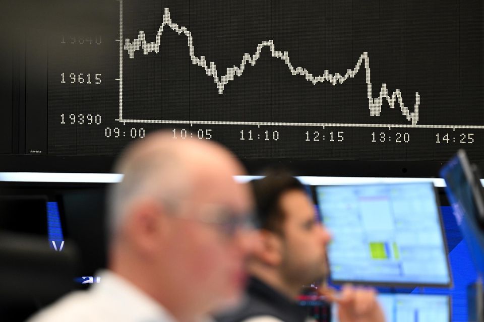 Börsenhändler beobachten auf dem Parkett der Frankfurter Börse vor der Anzeigetafel mit der Dax-Kurve ihre Monitore