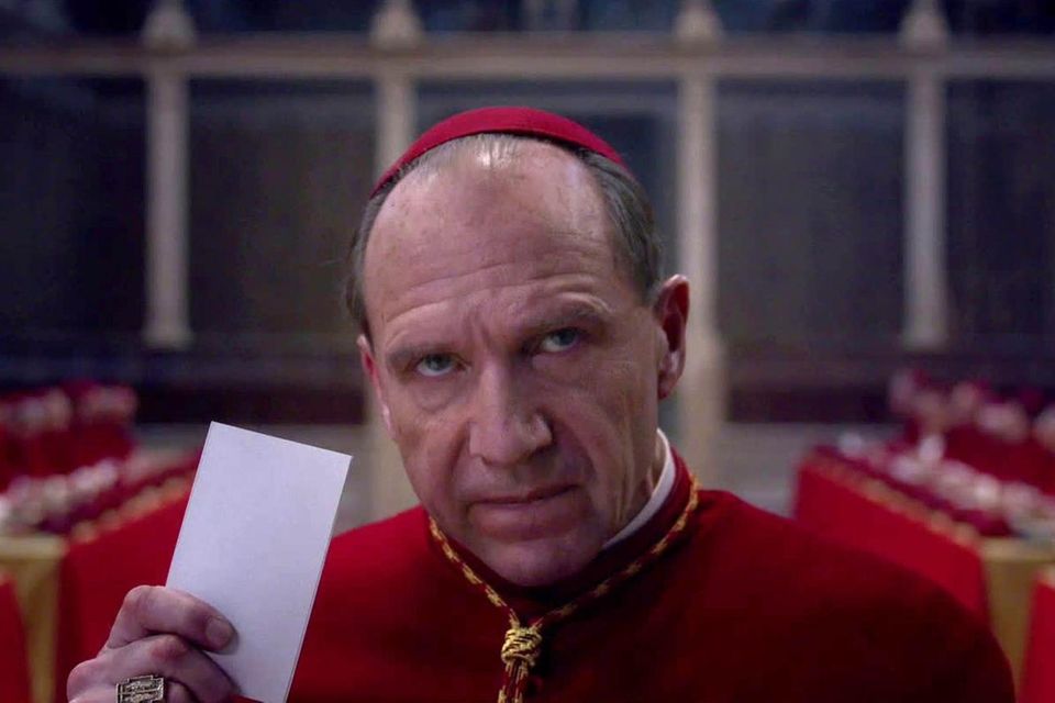 Ralph Fiennes spielt im Film einen Kardinal, der gerade einen Stimmzettel abgibt