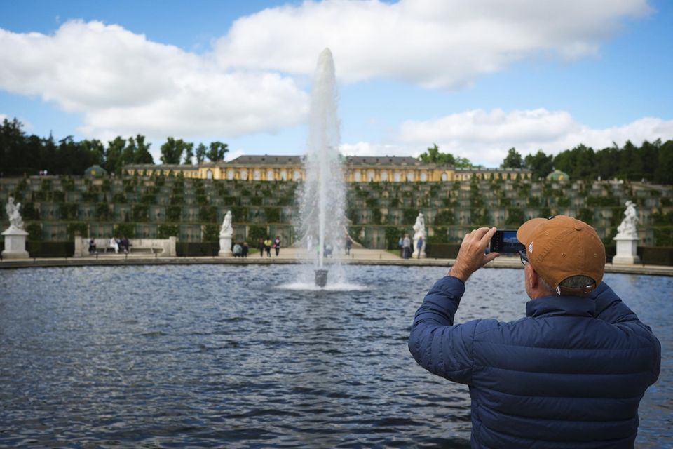 Ein Tourist fotografiert den Sanssouci Park in Potsdam