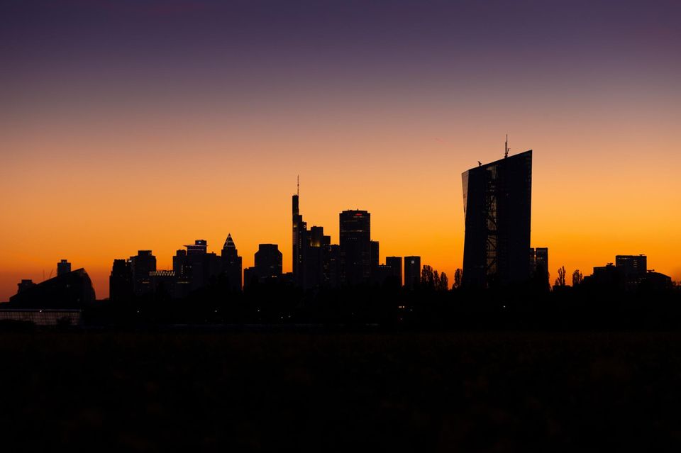 Die Silhouette der Frankfurter Bankenskyline zeichnet sich im leuchtenden Abendhimmel ab