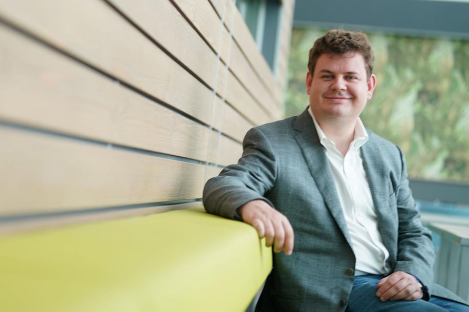 Nick Turley, Produktchef ChatGPT bei OpenAI, sitzt im Anzug auf einer Couch
