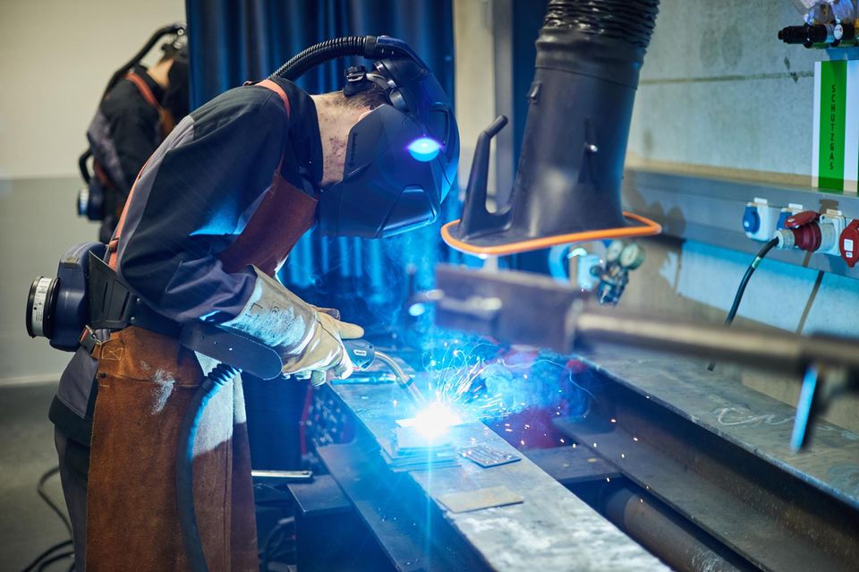 Ein Auszubildender zum Industriemechaniker schweißt Metall zusammen