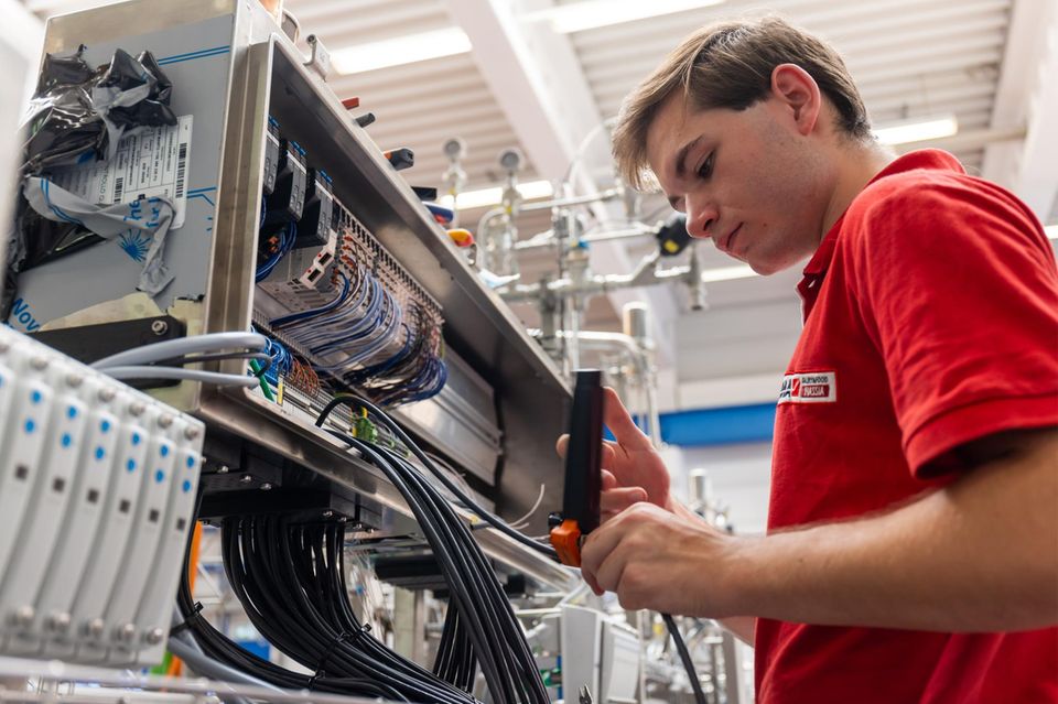 Ein Auszubildender zum Elektroniker verdrahtet einen Maschinenschaltschrank