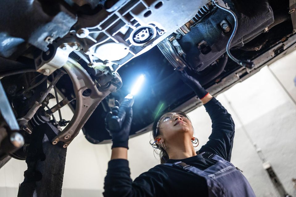 Eine Automechanikerin arbeitet an einem Auto