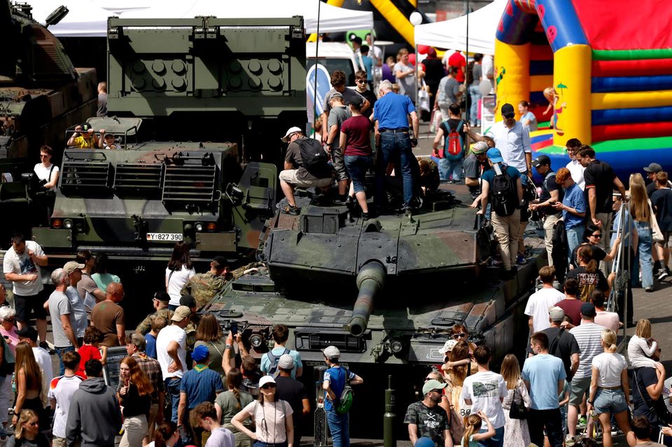 Besucher klettern am Tag der Bundeswehr auf einen Kampfpanzer, dahinter steht ein Raketenwerfer