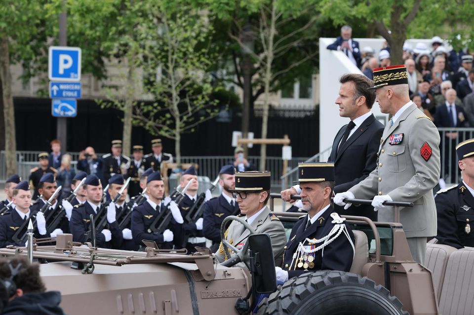 Frankreichs Präsident Macron fährt auf einem Militärjeep durch eine Parade
