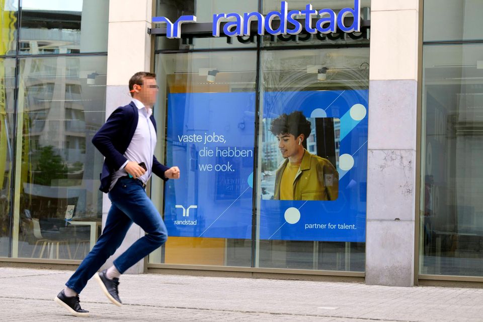 Ein Mann läuft an einem Schaufenster der Zeitarbeitsfirma Randstad vorbei