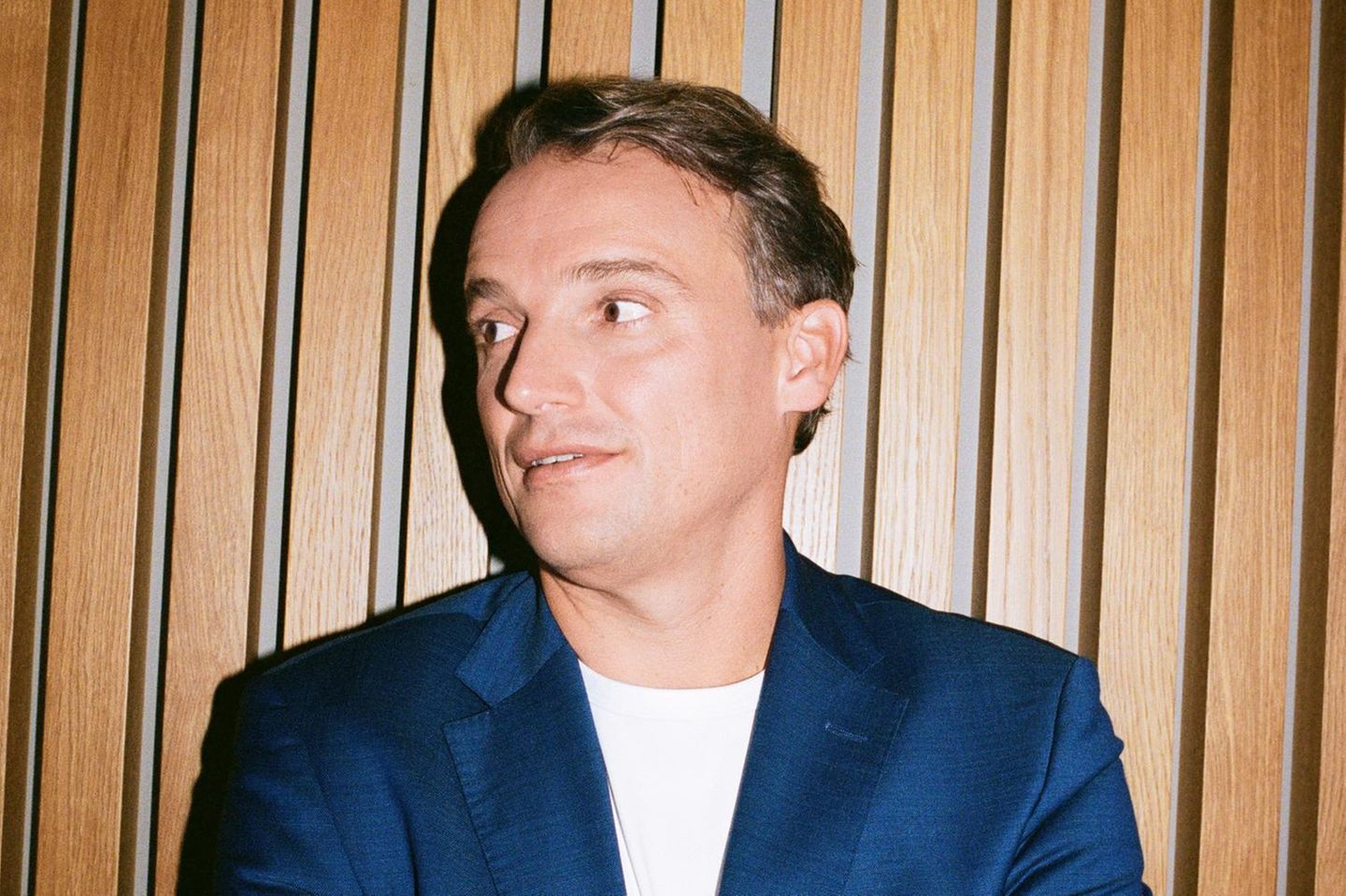Christian Klein steht mit verschränkten Armen vor einer Wand
