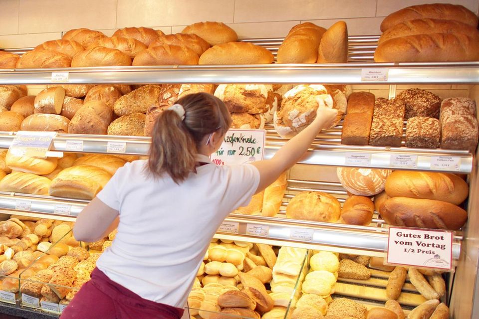 Piekarz bierze bochenek chleba z ekspozycji za ladą