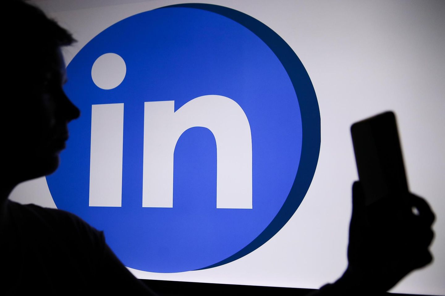 LinkedIn-Logo mit einer Person, die ein Telefon in der Hand hält