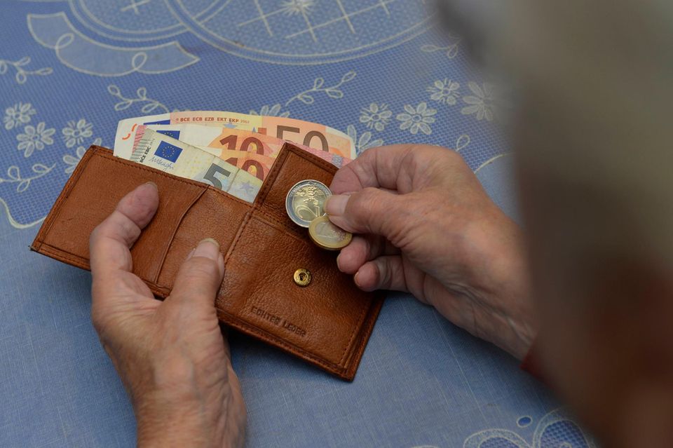 Bir kadın elinde birkaç madeni para ve bir cüzdan tutuyor