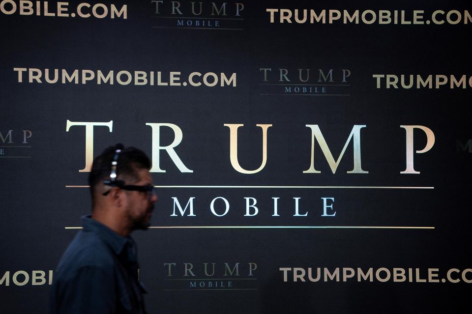 Ein Mann geht an einer Wand mit der Aufschrift „Trump Mobile“ vorbei