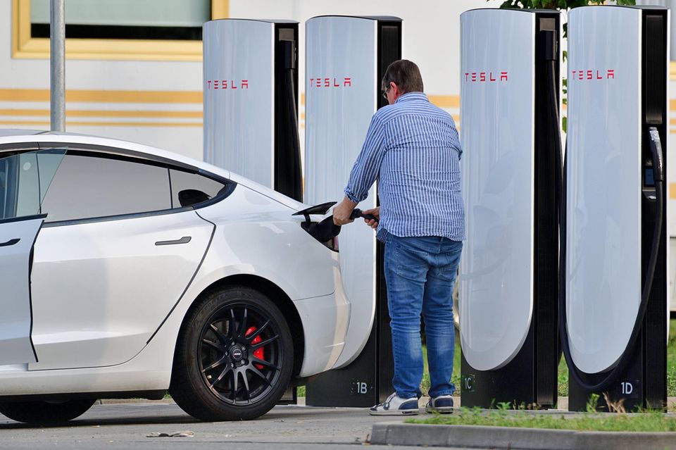 Fahrer eines E Autos lädt sein Auto an einem Tesla Supercharger