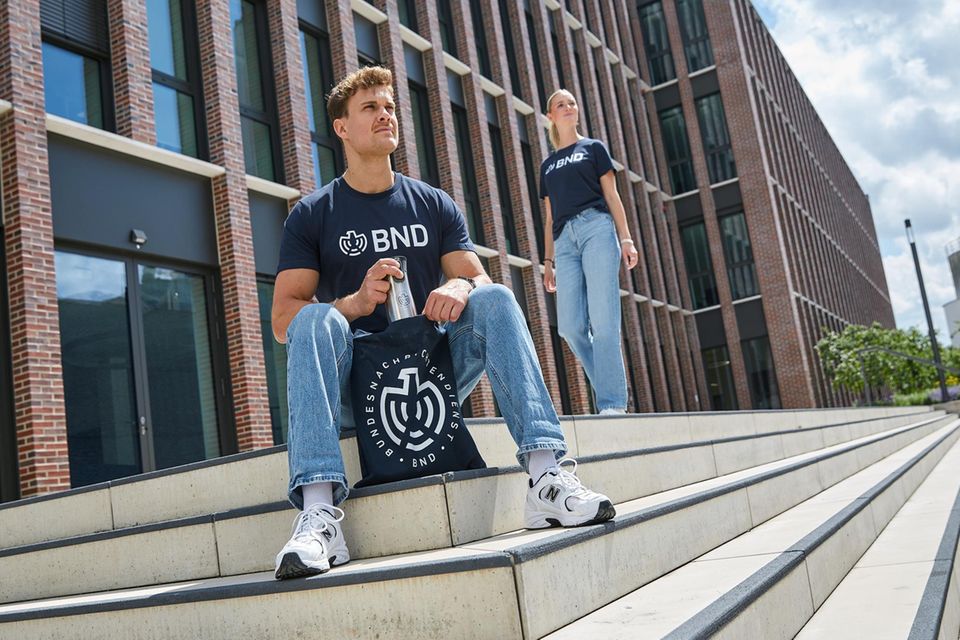 Ein Werbefoto des BND zeigt das T-Shirt, eine Tüte und einen Kaffeebecher