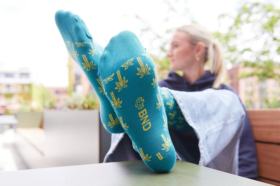 Auf einem Werbefoto streckt eine Person die Socken mit Palmen des BND in die Kamera