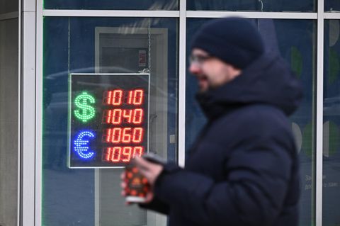 Mann geht an einer Tafel mit den Wechselkursen des US-Dollars und des Euros vorbei