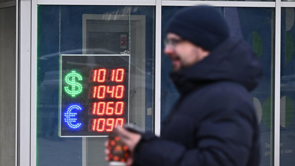 Mann geht an einer Tafel mit den Wechselkursen des US-Dollars und des Euros vorbei