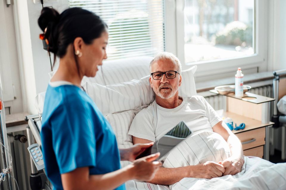 Eine Krankenschwester betreut und berät einen Patienten in einem Krankenhauszimmer