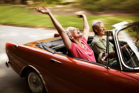 Ein älteres Paar fährt mit einem offenen Cabrio