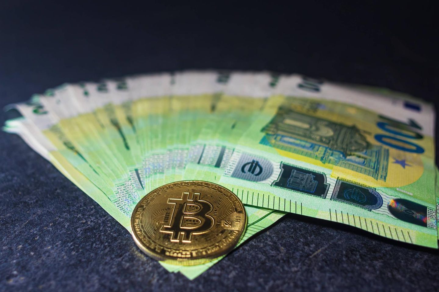 Goldene Bitcoin-Münze liegt bei 100 Euro-Scheinen