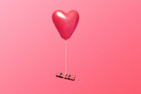 An einem herzförmigen Luftballon hängen zwei Dynamitstangen