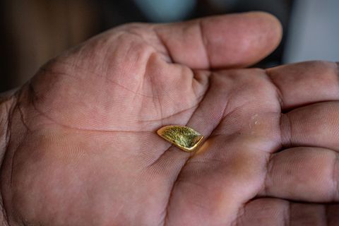 Ein kleines Goldstück liegt auf einer Handfläche