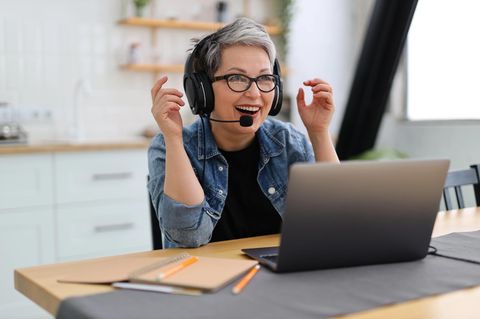 Eine Frau sitzt mit einem Headset auf dem Kopf vor ihrem Rechner
