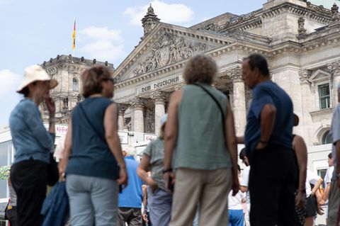 Vor dem Reichstagsgebäude in Berlin stehen Touristen